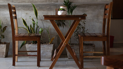 a table with two wooden chairs along with some plants inside a coffee shop in tulum mexico