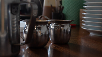 two metal coffee cups on a wooden table inside a coffee shop in tulum mexico