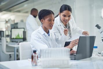 Improving lives one collaboration at a time. Shot of two young scientists using a laptop in a...