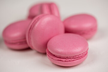 Obraz na płótnie Canvas Macarons closeup on white wooden background. Sweet and colourful pink french macaroons. Cooking at home.