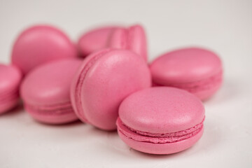 Macarons closeup on white wooden background. Sweet and colourful pink french macaroons. Cooking at home.