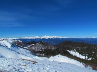 View of mountain Triglav summit and surrounding mountains in the Julian alps, Gorenjska, Slovenia in winter taken from Ratitovec on a clear blue day