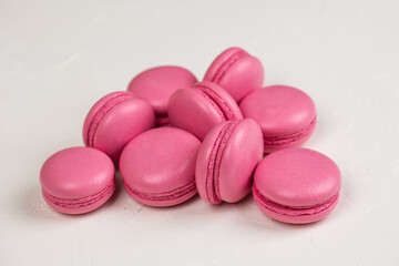 Macarons closeup on white wooden background. Sweet and colourful pink french macaroons. Cooking at home.