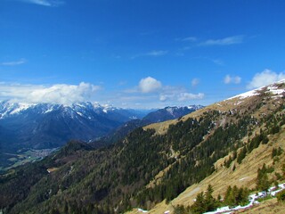 View of mountains in Julian alps covered in snow and shrouded in clouds above Mojstrana village in...