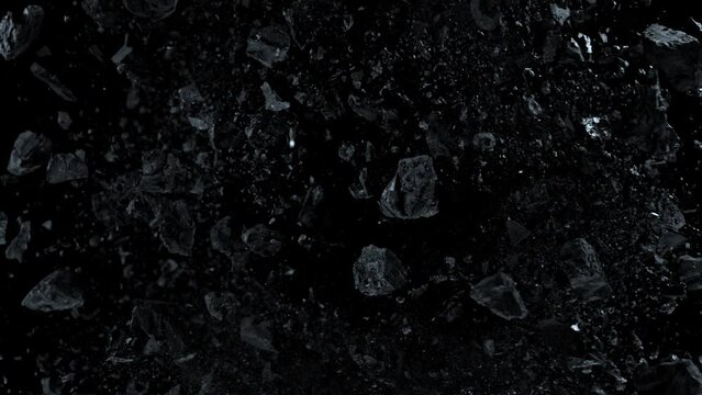 Super slow motion shot of rotating exploded scattered coal on black at 1000fps.