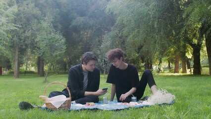 Two young guys looking at the phone in nature in the summer. LGBT