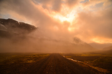 Naklejka na ściany i meble A misty and moody sunset on the mountain road to the to Mjóifjörður fjord, East Fjords, Iceland