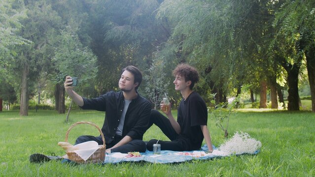 Two young guys are photographed on the phone in nature in the summer. LGBT