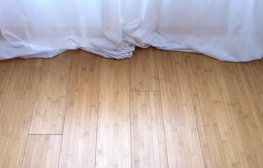 white curtain trailed on a bamboo parquet floor