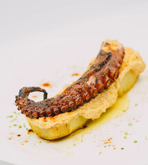Una ración gourmet de tentáculo de pulpo sobre patatas al horno
