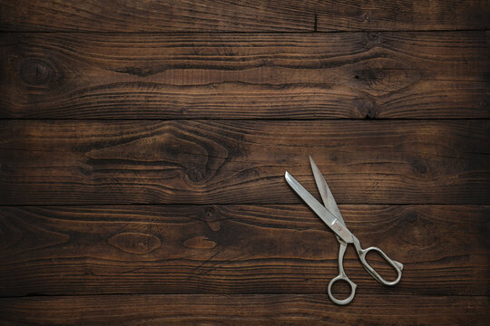 Tailoring scissors on dark wooden table. Copy space for text. Top view.