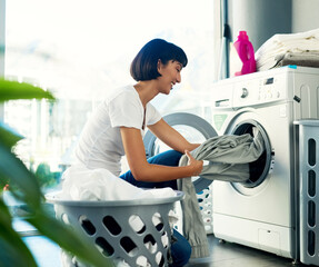 I enjoy doing my own laundry. Shot of a young woman doing her laundry at home.