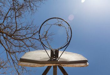 Rusty old double basketball hoop in the park, outdoor recreation area.