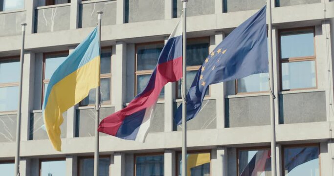 Ukrinian flag waves with Slovenian and European at parliament facade