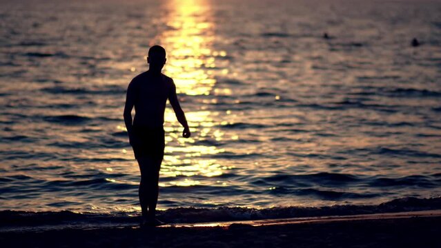 Silhouette of flexible fit man doing a backflip on the sandy beach at sunset