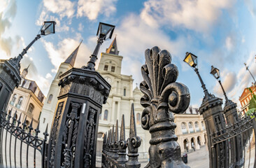 Fototapeta na wymiar Closeup of a fleur de lis symbol, part of the historic wrought iron gate in Jackson Square. Fisheye, distorted view. Very shallow focus for effect on the 3rd leaf. St. Louis Cathedral blurred beyond.