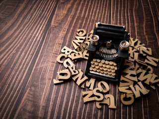 Wooden word and vintage black typewriter on the wooden background.