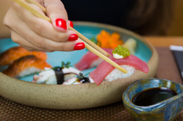 Obraz na płótnie Canvas Woman eating delicious sushi, closeup on chopsticks.