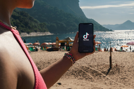 Girl on the beach holding a smartphone with Tik Tok app on the screen. Rio de Janeiro, RJ, Brazil. March 2022