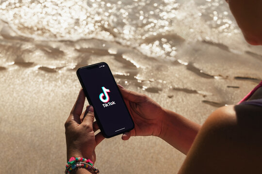 Girl on the beach holding a smartphone with Tik Tok app on the screen. Rio de Janeiro, RJ, Brazil. March 2022