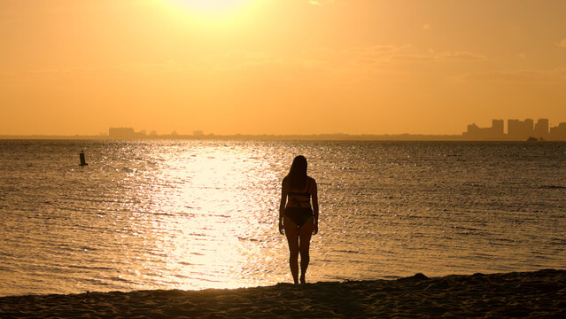 Young woman wearing a bikini at the beach on sunset over Miami