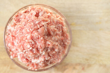 minced pork. fresh raw minced meat close-up in a transparent cup on a wooden table. Meat...
