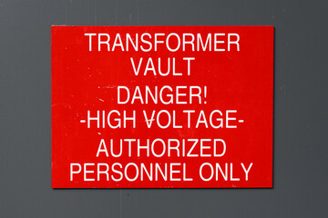 Red sign with white letter informing Transformer Vault Danger, High Voltage, Authorized Personnel...