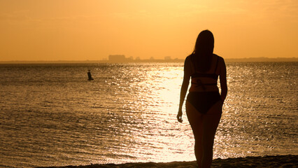 Silhouette shot of a beautiful woman on sunset shot against the golden ocean water