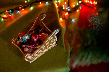 Naklejka premium Christmas gingerbread sledges with candies and bokeh light garland. Christmas food. Top View.