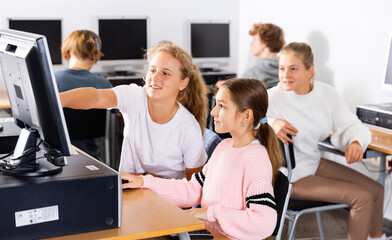 Portrait of two schoolgirls engaged in the classroom at a informatics lesson at the computer