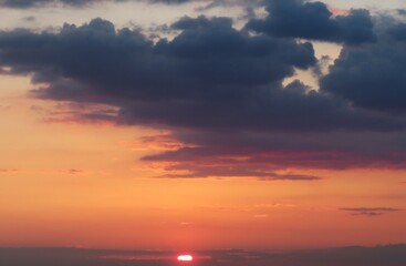 Beautiful orange fiery sunset in the sky with dark clouds