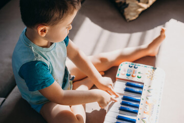 Toddler boy having fun playing piano toy in his free time. Hobby concept. Education concept.