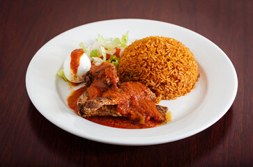 West African entree of jollof rice with fish and salad in a white plate