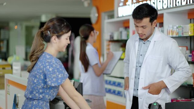 caucasian male pharmacist explaining the medicinal properties on the pillbox to a patient or customer according to the doctor's prescription and providing customers with e-service payment at the custo