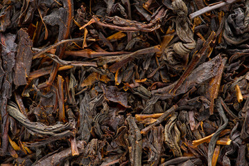 Black large-leaf tea as abstract background. Texture of dry black tea leaves. Dark background. Macro black tea leaf