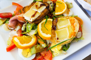 French cuisine. Salad with goat cheese, oranges, vegetables and honey