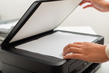 Woman hand putting white paper in printer, scanner,  copy machine, office document, photocopier.