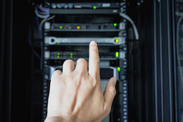 hand of man operating server cabinet via digital control panel in data center