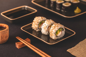 sushi roll sul piatto nero con le bacchette	