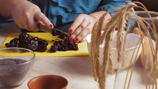 Women's hands cut prunes for Gomentashi cookies with poppy seeds for the Purim holiday