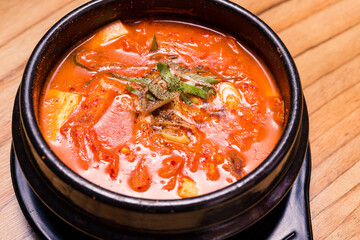 Kimchi soup in hot black iron pot, Korean traditional Kimchi Jjigae soup in bowl in the restaurant, Japanese hot pot food
