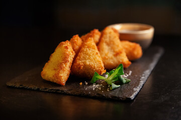 Golden delicious fried nuggets with sauce on a dark background