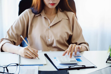 Financial and investment auditing concept, female auditor is pressing calculator to check budget...