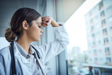 Burnout is rampant amongst medical professionals. Shot of a young female doctor looking stressed...