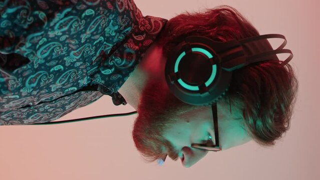 profile shot millennial caucasian bearded gamer in a patterned shirt with computer light on his face vertical studio shot. High quality 4k footage