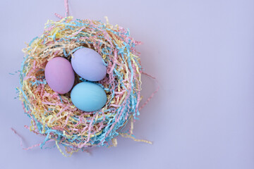 View from above. Nest with colorful Easter eggs. There is space for text. Pastel shades