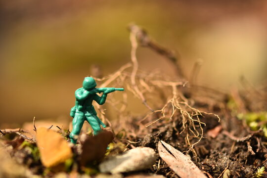 Toy soldier in the forest shows the concept of a one-man army. Camouflage man with a gun in the forest. 