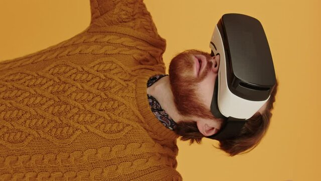 caucasian hipster with ginger beard in a sweater wearing VR headset glasses and moving his head around. High quality 4k footage