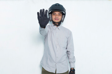 handsome asian man with a motorcycle helmet open hand doing stop sign with serious expression defense gesture isolated on white background
