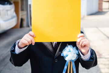 卒園児と卒園証書ファイル。卒園式コサージュ。スーツを着た幼児。